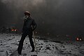 Protester walking through Grushevskogo str. covered with smoke of the fire set by the protesters to prevent internal forces from crossing the barricade line. Kyiv, Ukraine. Jan 22, 2014