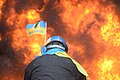 Protester wearing Ukraine state flag colors facing the massive fire set by protesters to prevent internal forces from crossing the barricade line. Kyiv, Ukraine. Jan 22, 2014