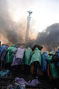 Protesters holding protective positions behind an improvised wooden shields right in the middle of the Central Square, Independence Monument is seen on the background, covered with smoke. Clashes in Ukraine, Kyiv.