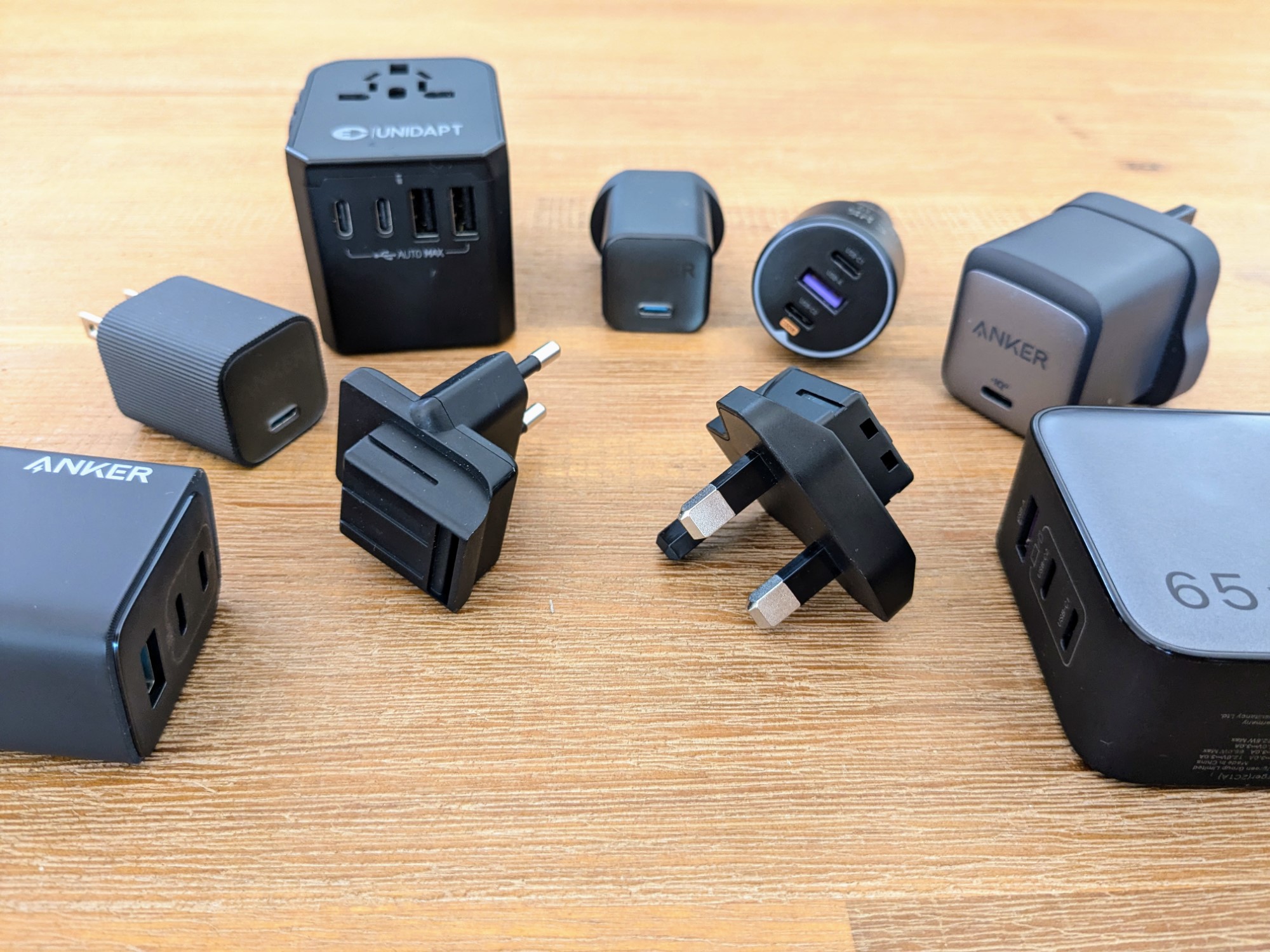 Many chargers and plug adapters on a wooden table
