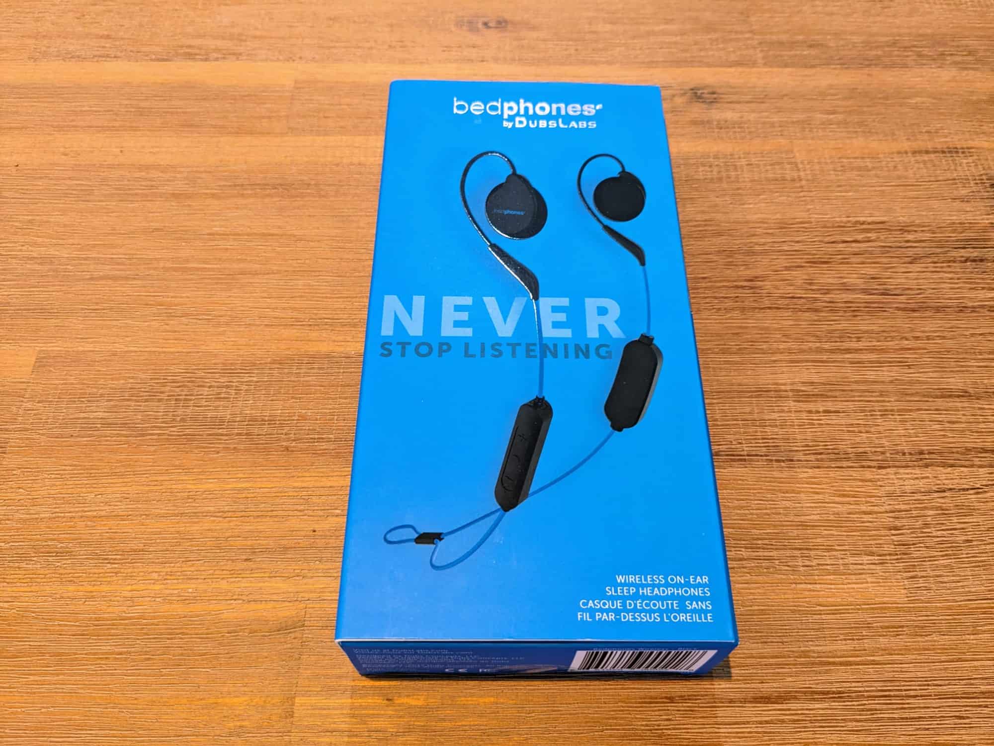 Rectangular blue box on a wooden table, with "Bedphones by Dubslabs" at top, a photo of a pair of earphones in the middle with text "Never stop listening" overlaid on top.