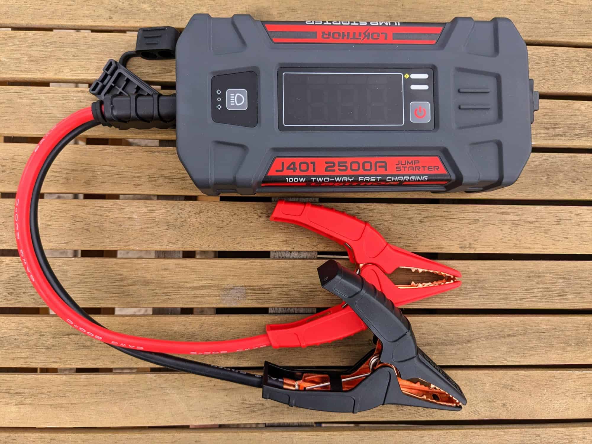 Lokithor J401 portable jump starter on wooden table with two short jumper leads attached