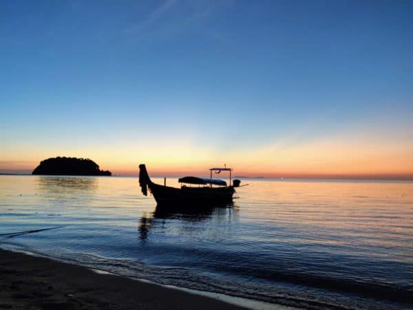 Longtail boat pulled up on the beach at sunset in Thailand