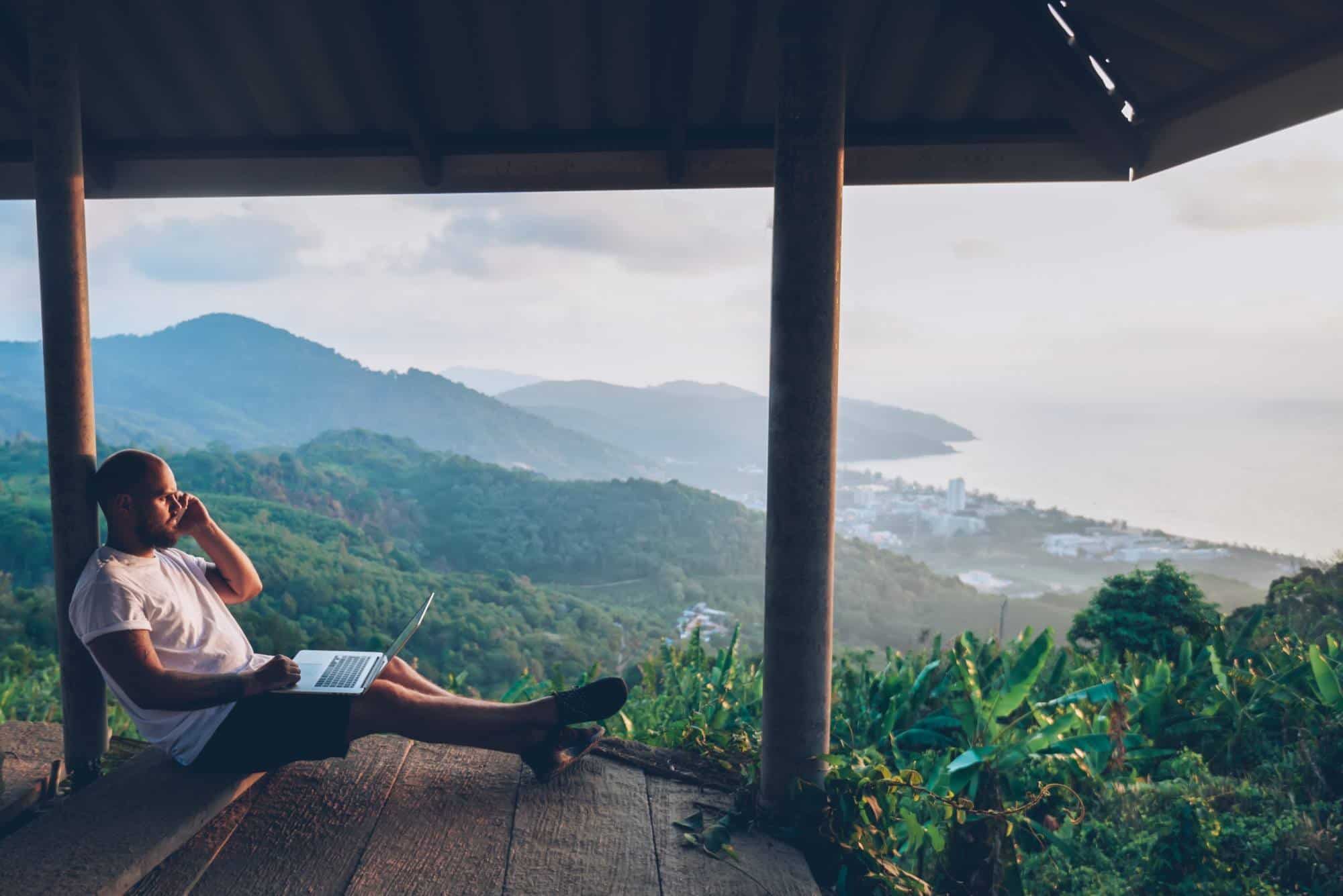 Man using laptop with jungle view