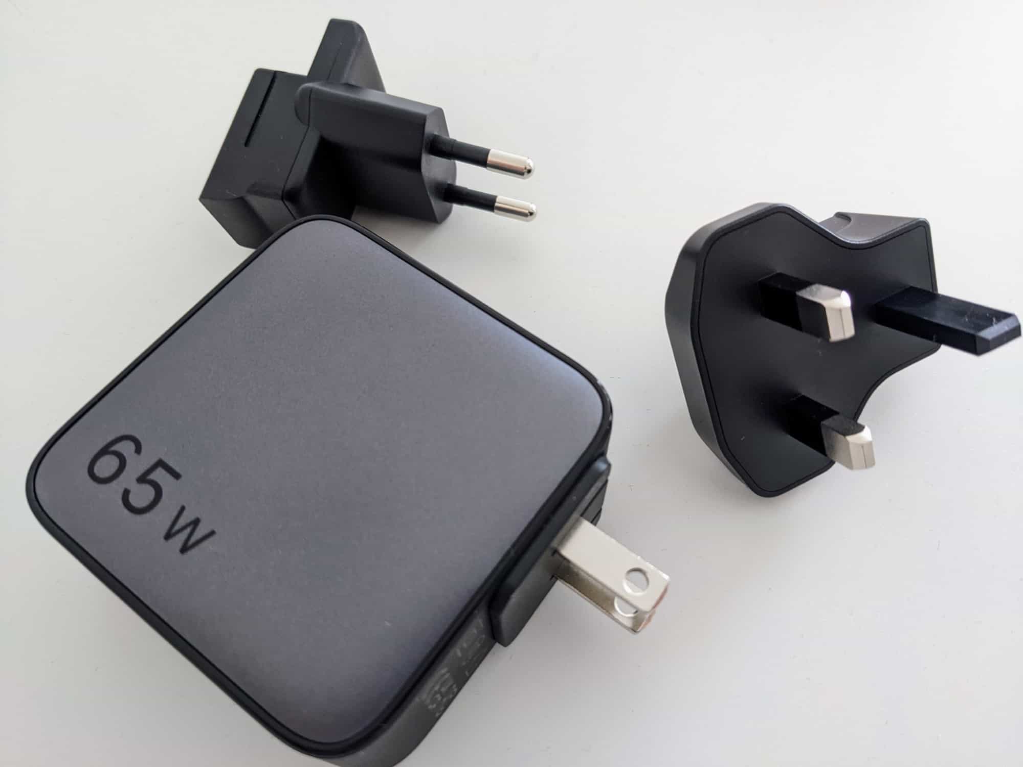 UGreen 65W travel charger on white table - US plug inserted, other two plugs alongside