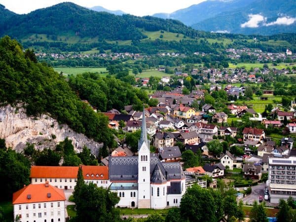View from above of the town of Bled in Slovenia, with a church in the foreground and fields and mountains in the background