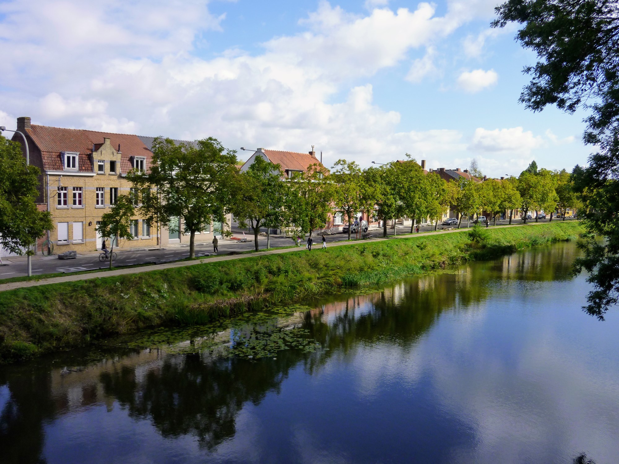 View over the Kasteelgracht body of water towards the opposite tree-lined bank and a row of houses in Ypres, Belgium.